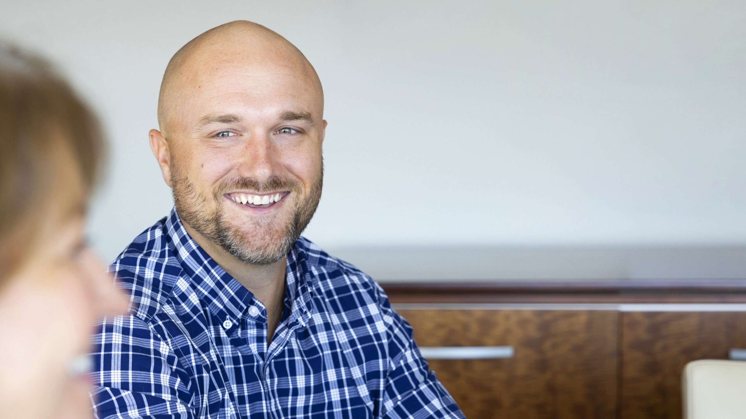 A smiling man sitting across a table from a woman.