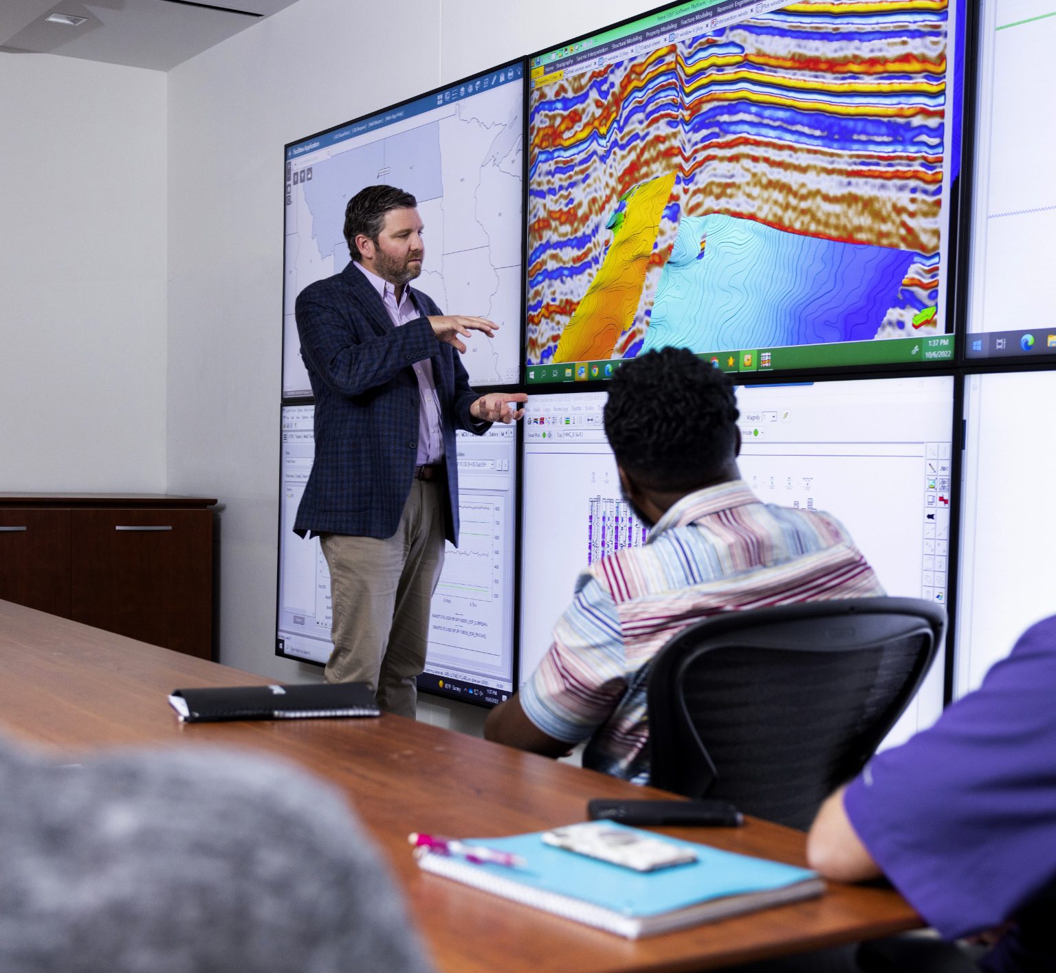 A man discussing Denbury's operations in front of a set of screens.